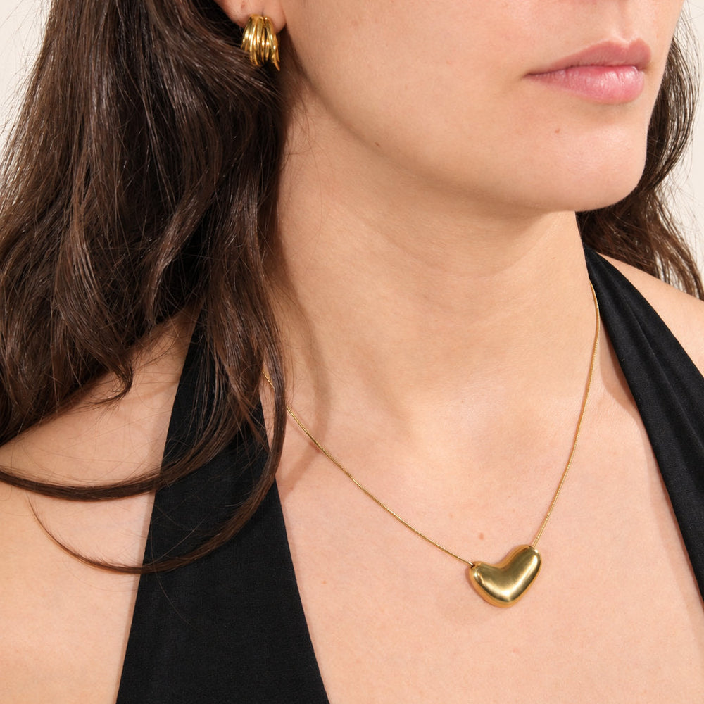Pormenor de um colar dourado com pendente em coração