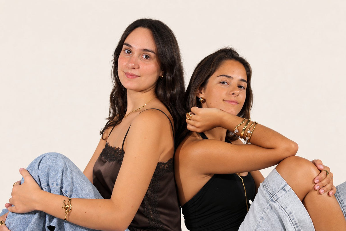 Modelo com anéis, colares e brincos MIIMU, com o rosto apoiado nas mãos